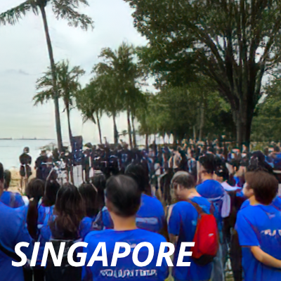 A large group of Alcon volunteers in Singapore meeting on a beach