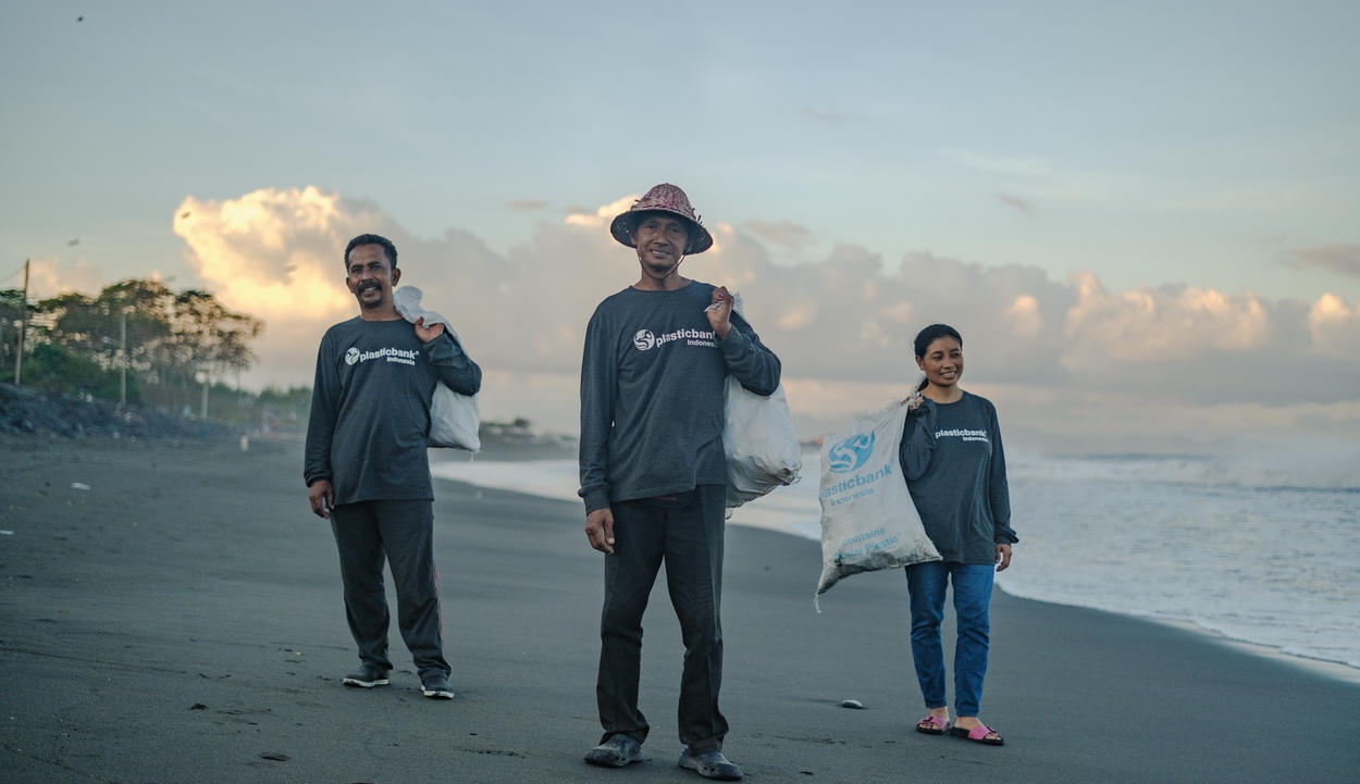 Three people in Indonesia collecting plastic along beach