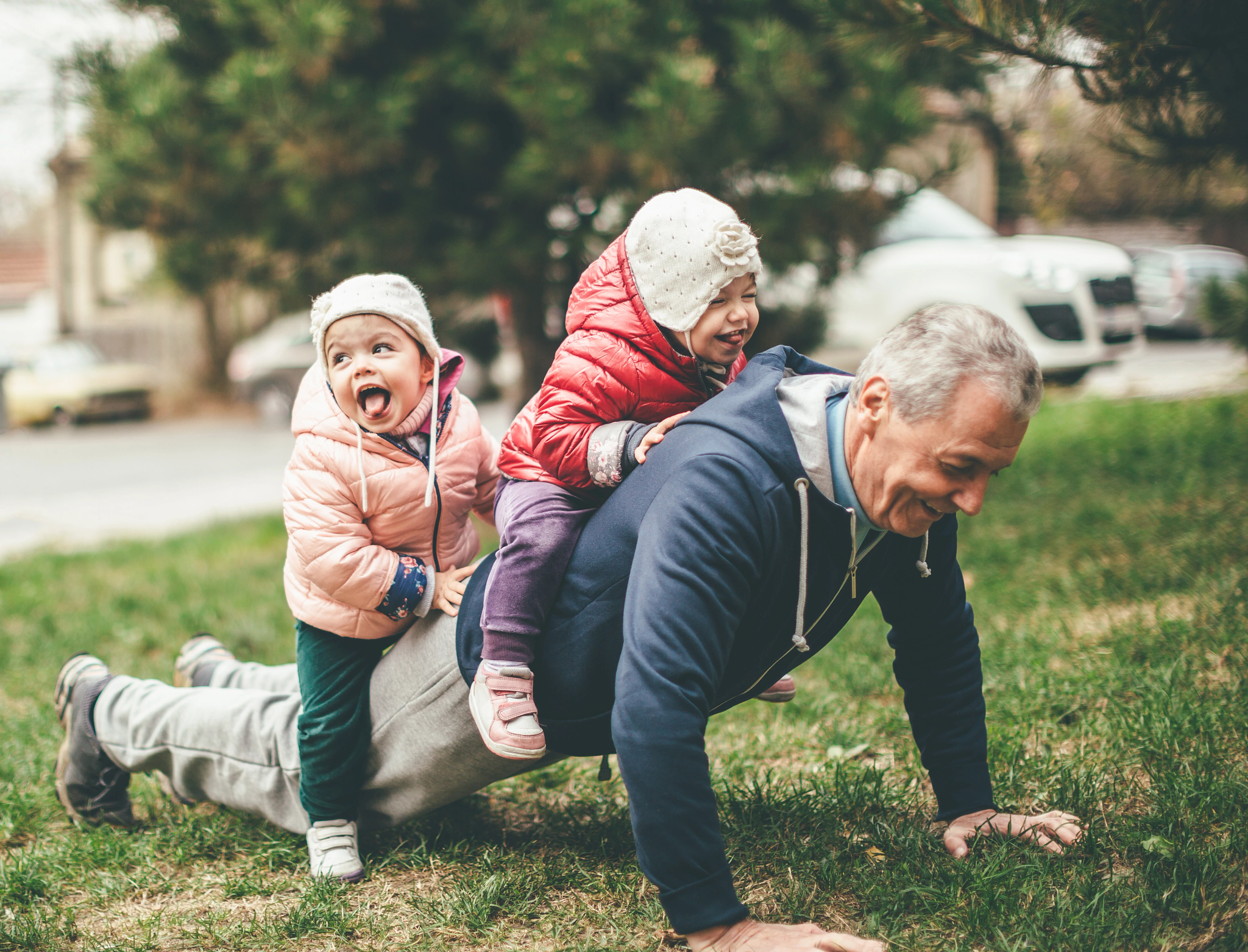 Older man with 2 small children riding on his back.