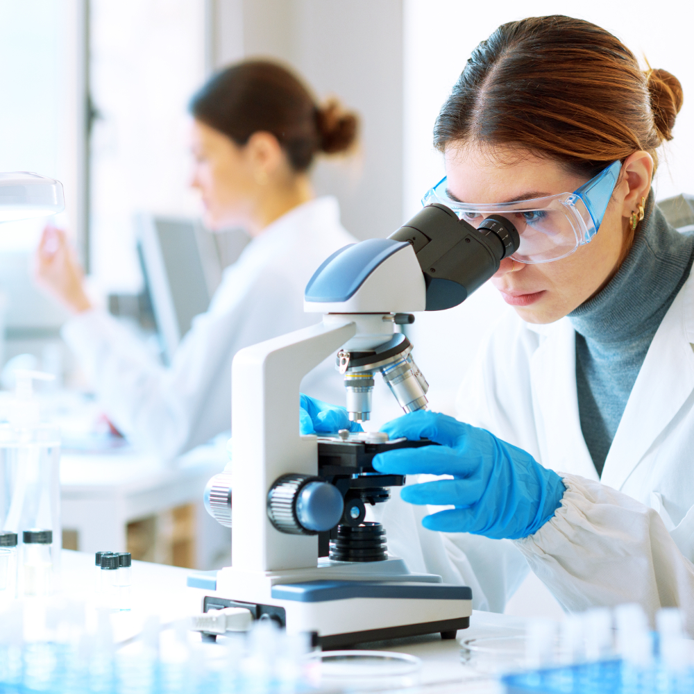 Woman examining a sample under a microscope.
